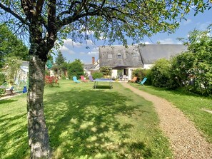 A backyard with a ping pong table, a tree, and a house in the background. - Cottage 'La Grange Soleil' with Private Terrace, Wi-Fi and Air Conditioning (Veigné)