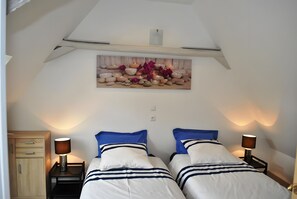 A bedroom with two beds, a wooden cabinet, and a wall-mounted painting.