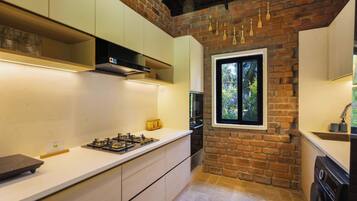 A kitchen with a brick wall, a window, and a modern stove.