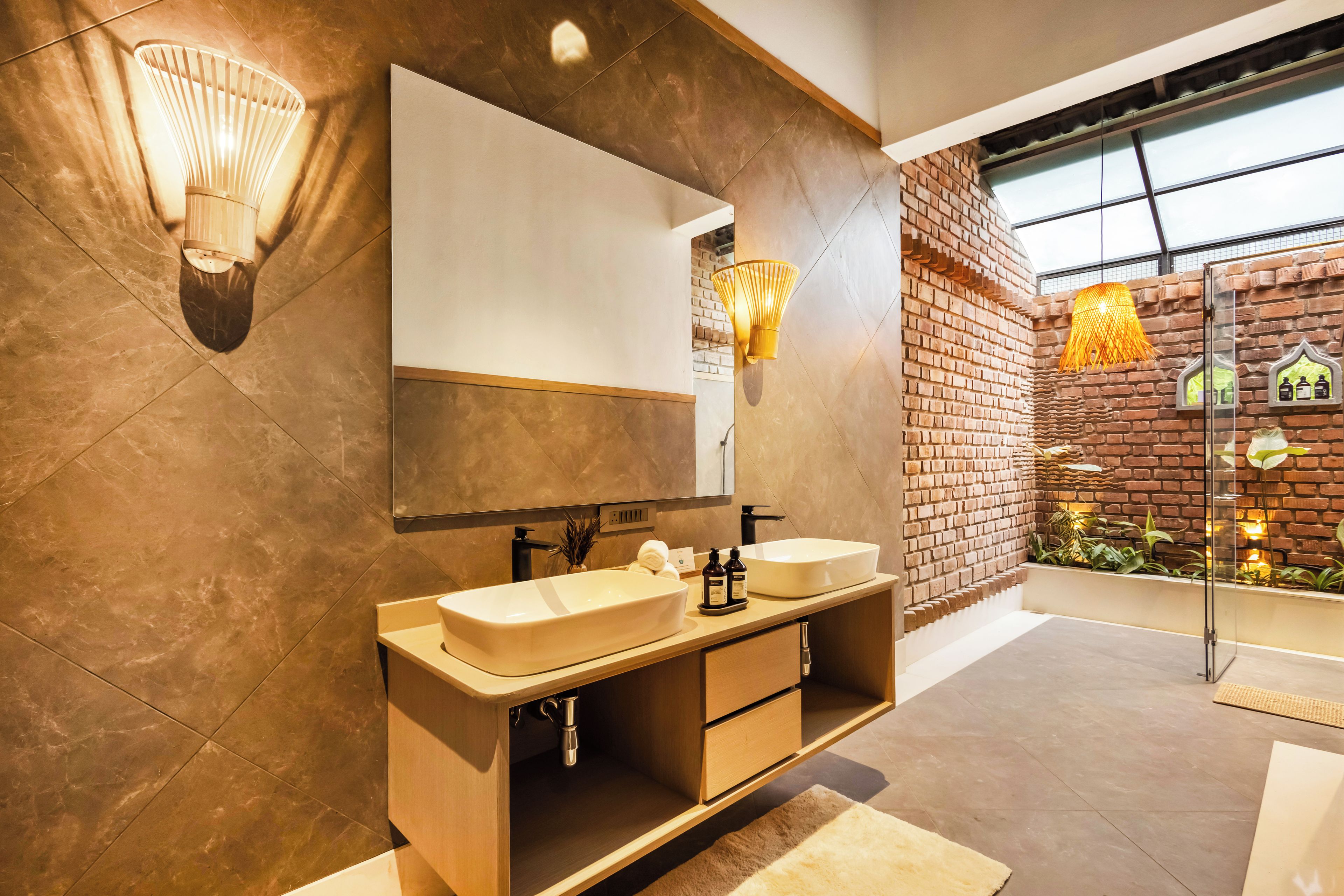 Une salle de bain moderne avec deux lavabos, un grand miroir et un mur d’accent en briques.
