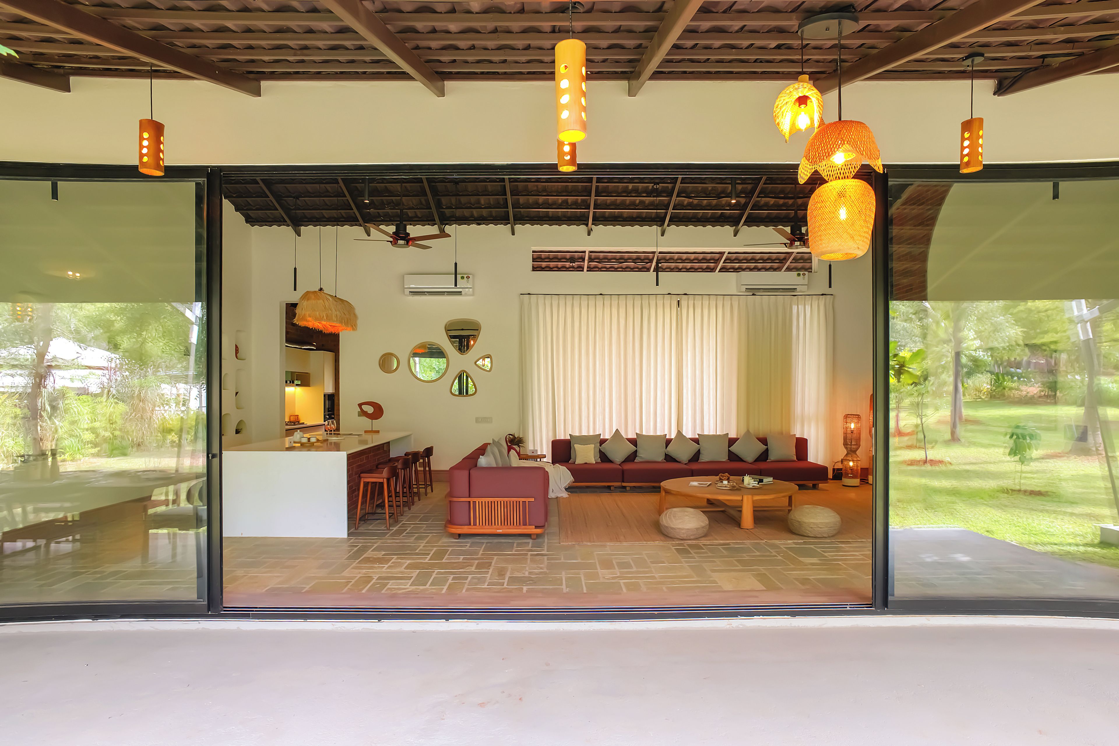 A modern interior with a dining area, a living room with a sofa and coffee table, and a large glass wall offering a view of the outdoors.