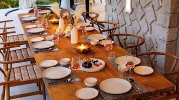A long wooden dining table set for a meal with candles, plates, and glasses.