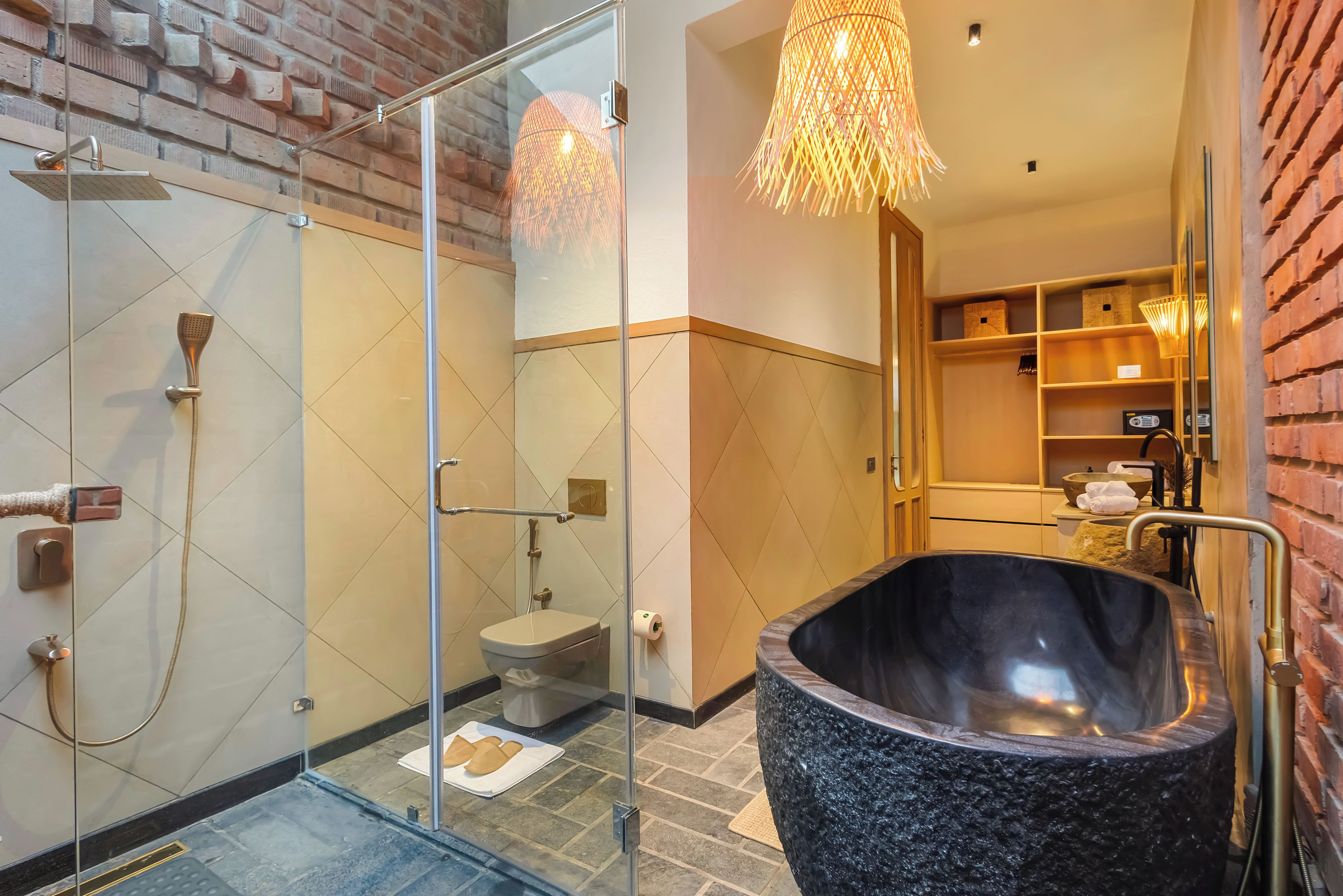 A modern bathroom with a glass-enclosed shower, a freestanding bathtub, and a brick wall.