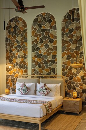 A bedroom with a stone wall, a wooden bed frame, two bedside tables, and a hanging light fixture. - ELIVAAS Prive Saukhyam 3BHK Villa (Bengaluru)