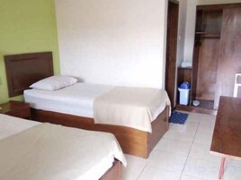 Habitación de hotel con dos camas, cabecera de madera, un escritorio pequeño y un armario.