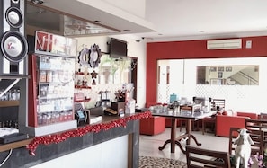 A dining area with a long table, chairs, and a red accent wall. - Nirwarna Hotel Bojonegoro (Bojonegoro)