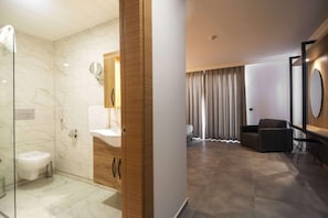 A modern bathroom with a glass shower enclosure, a wooden vanity, and a mirror. - Grand Kolibri Prestige and Spa (Alanya)