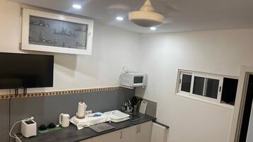 A kitchen with a microwave, toaster, and a framed cityscape picture on the wall.