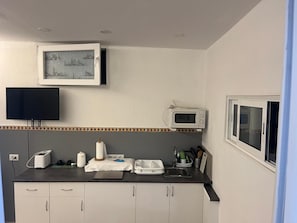 A kitchen with a flat-screen TV, a microwave, a sink, and cabinets. - Vacation Apartment 'Estudio Kylie' with Sea View, Wi-Fi and Air Conditioning (Santa Cruz de Tenerife)