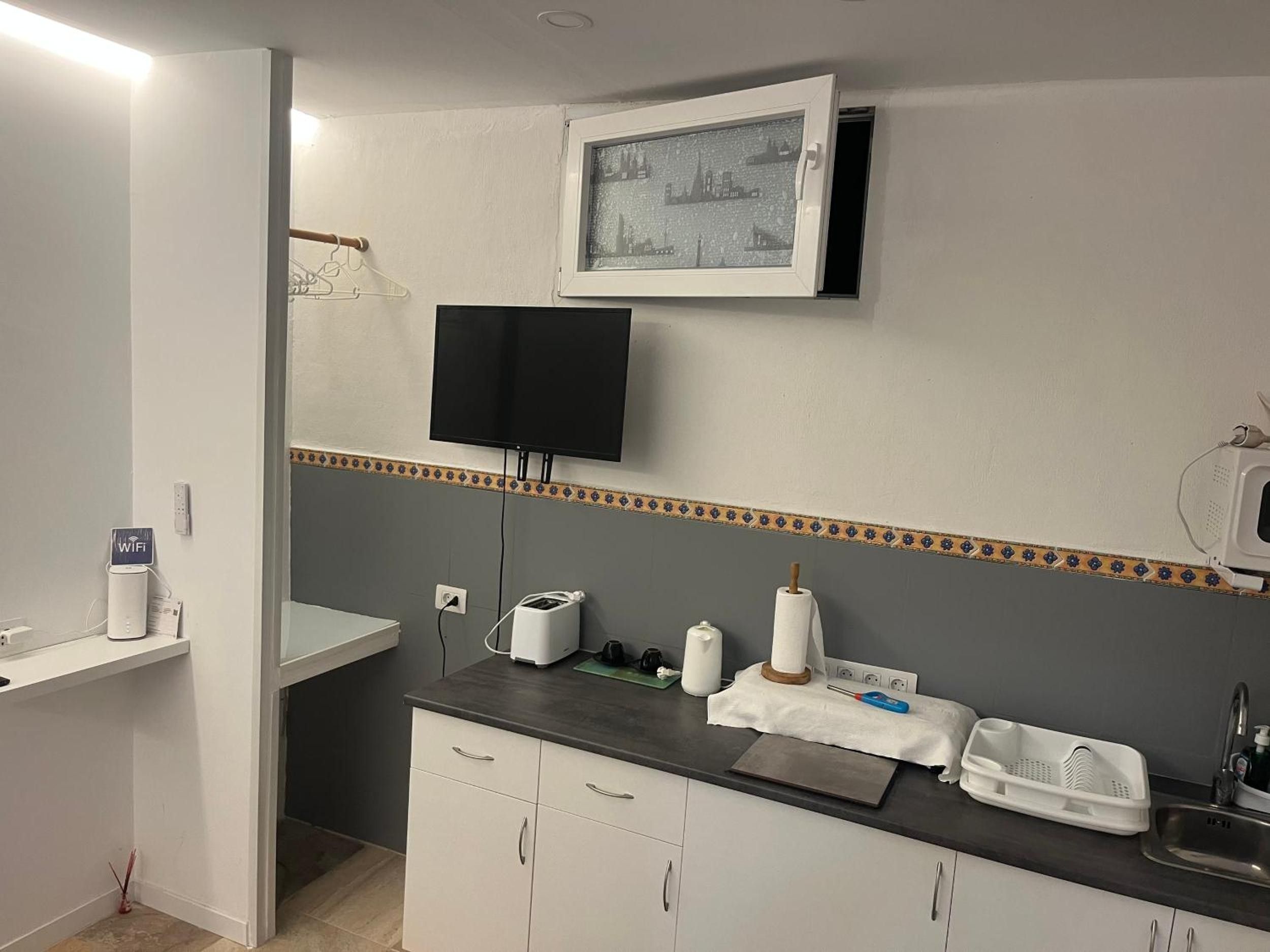 A compact kitchenette with a flat-screen TV, a small sink, and a microwave.