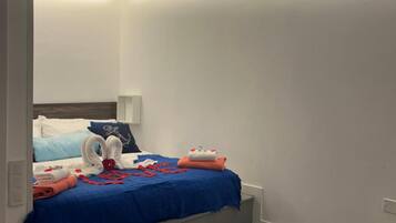 Een hotelkamer met een stapelbed, een klein bureau, een stoel, een nachtkastje en een plafondventilator.
