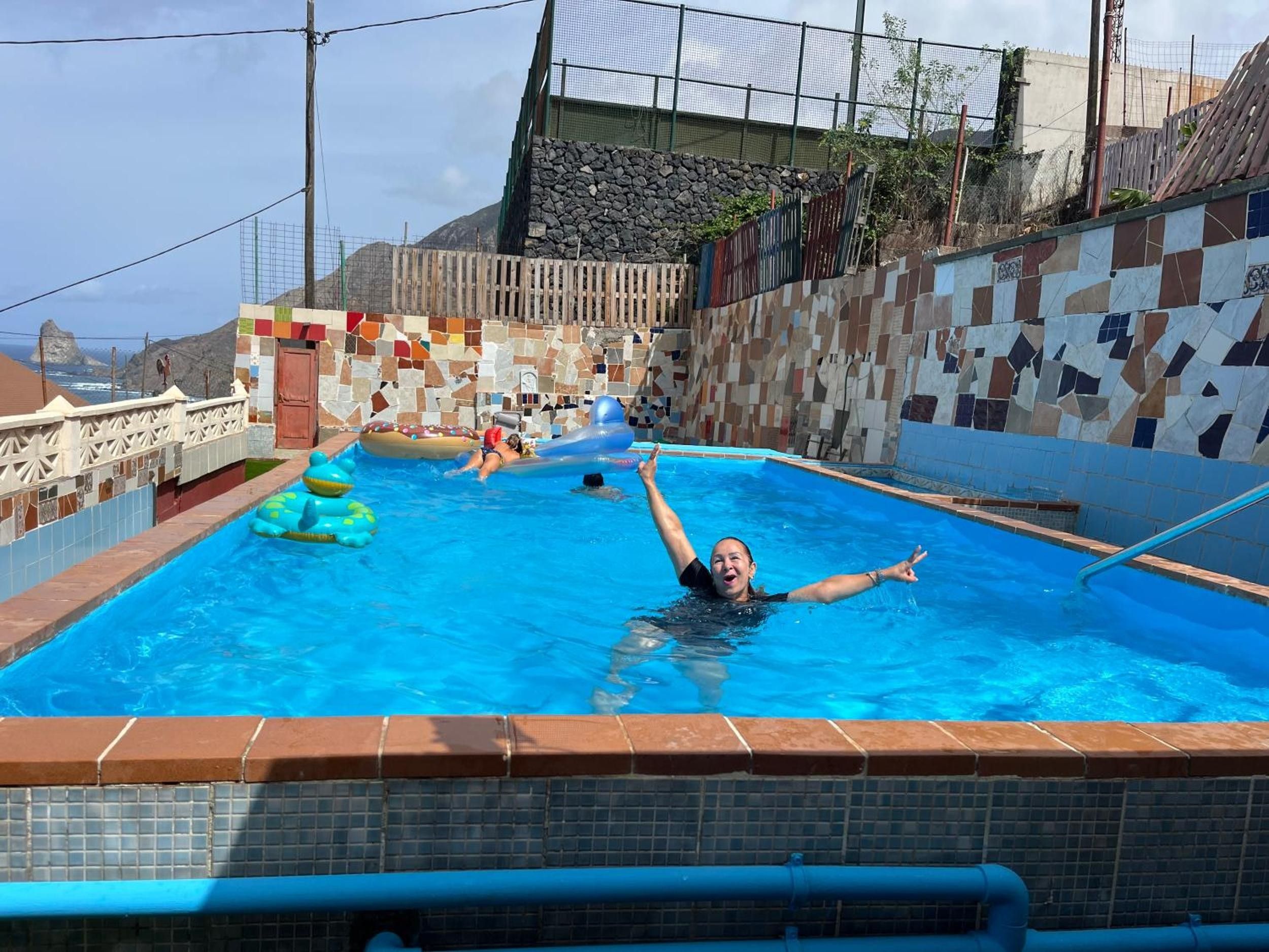 Ein Schwimmbad mit einer gefliesten Wand und Blick auf das Meer.