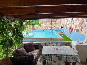 A pool area with a view of a cityscape, a wicker sofa, a table with a patterned tablecloth, and a tiled wall. - Vacation Apartment 'Estudio Kylie' with Sea View, Wi-Fi and Air Conditioning (Santa Cruz de Tenerife)