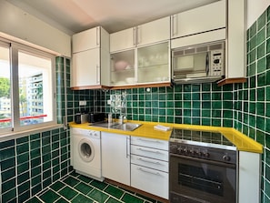 Eine kleine Küche mit Waschmaschine, Mikrowelle und Backofen.