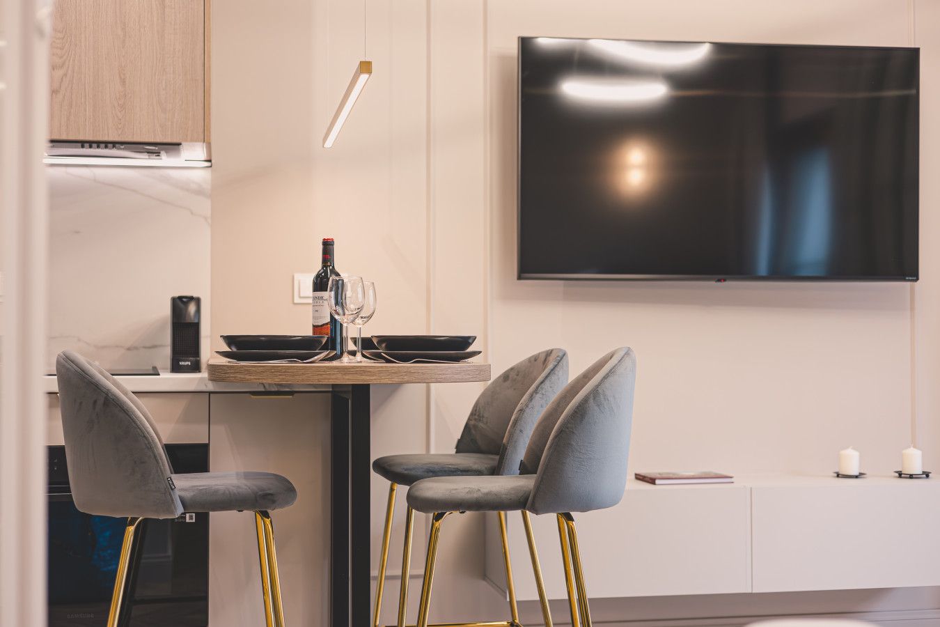 Een moderne keuken met een eethoek, een flatscreen televisie en een fles wijn.