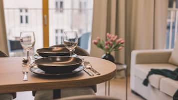 Mesa de comedor servida con platos, cubiertos y vasos, con vista a edificios y un florero al fondo.