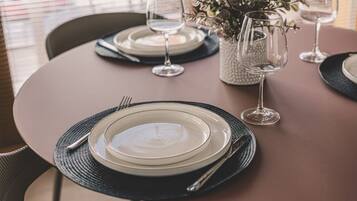 Una mesa redonda lista para comer, con platos, cubiertos y vasos.