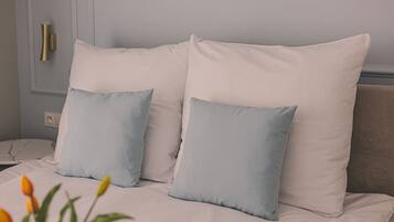 A bed with white bedding and two light blue pillows.