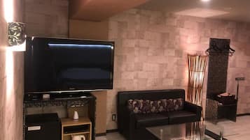 A living room with a flat-screen TV, a sofa, a coffee table, and a fireplace.