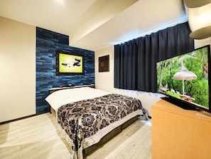 Un dormitorio moderno con una cama, un televisor y un televisor montado en la pared.