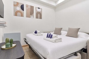 Ein Hotelzimmer mit einem Bett, Kissen, einem Nachttisch mit Spiegel und einem Kaktus auf dem Tisch.