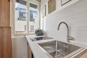 A modern kitchen with two stainless steel sinks, a window with a view of buildings, and a small appliance on the counter. - Elegant Renovated Suite – Montorgueil Center Paris (Paris)