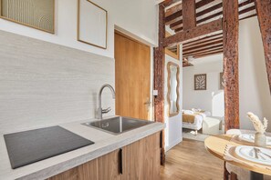 A modern kitchen with a built-in sink, wooden cabinets, and a dining area with a round table set for two. - Elegant Renovated Suite – Montorgueil Center Paris (Paris)
