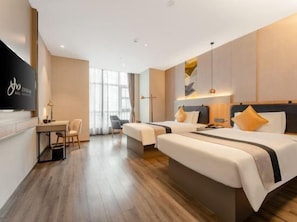 Habitación de hotel con dos camas, un escritorio y televisión.