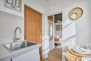 Eine moderne Küche mit einer Edelstahl-Spüle, einer Holztür und einer Wanduhr.