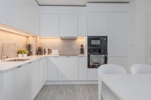Una cocina moderna con armarios blancos, horno integrado y microondas.