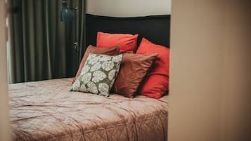 Una cama con cubrecama acolchado, cabecera y lámpara.