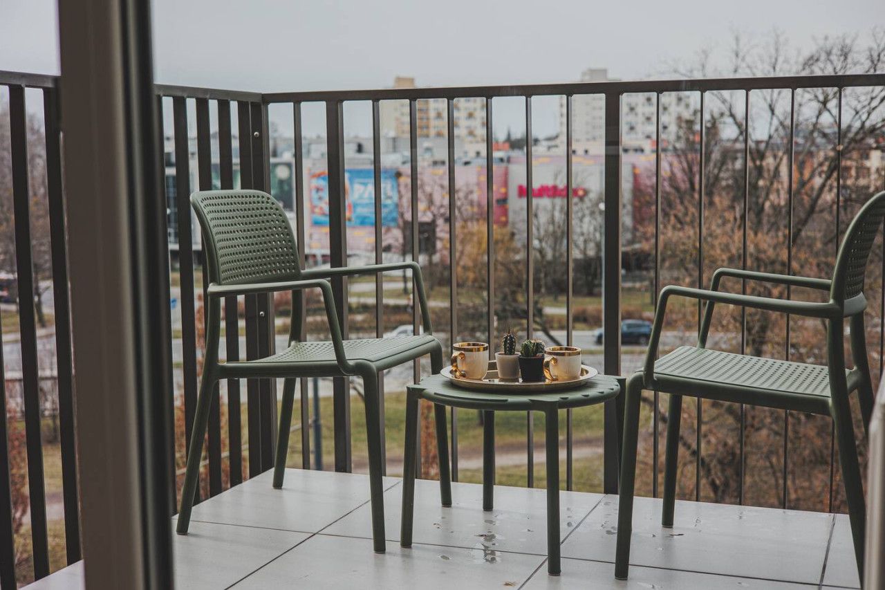 Un balcon avec deux chaises et une petite table sur laquelle se trouve un plateau avec divers objets.