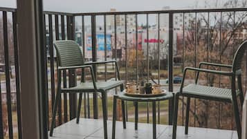 Un balcon avec deux chaises et une petite table sur laquelle se trouve un plateau avec divers objets.