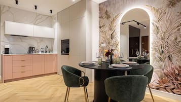 Una cocina moderna con armarios blancos, salpicadero de mármol y un comedor con una mesa redonda para cuatro.