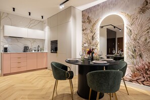 A modern kitchen with white cabinets, a marble backsplash, and a dining area with a round table set for four. - Garbary 5 Bydgoszcz by 2HomeRent (Bydgoszcz)