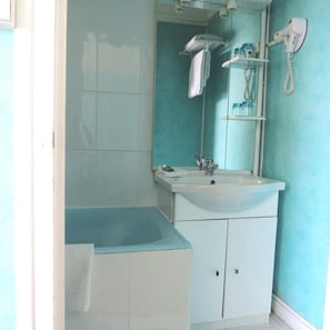 Un baño con un lavamanos blanco, un espejo, un perchero y un secador de pelo en la pared.