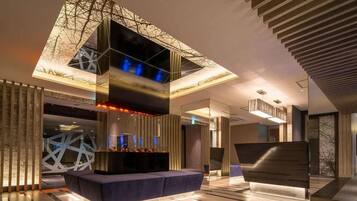 A modern interior with a central seating area, a geometric wall design, and a ceiling with a unique light fixture.