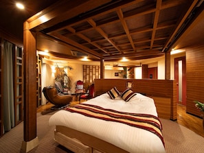 A hotel room with a large bed, wooden headboard, and a seating area with chairs and a sofa. - Kobe Leisure Hotel U's Koroen (Nishinomiya)