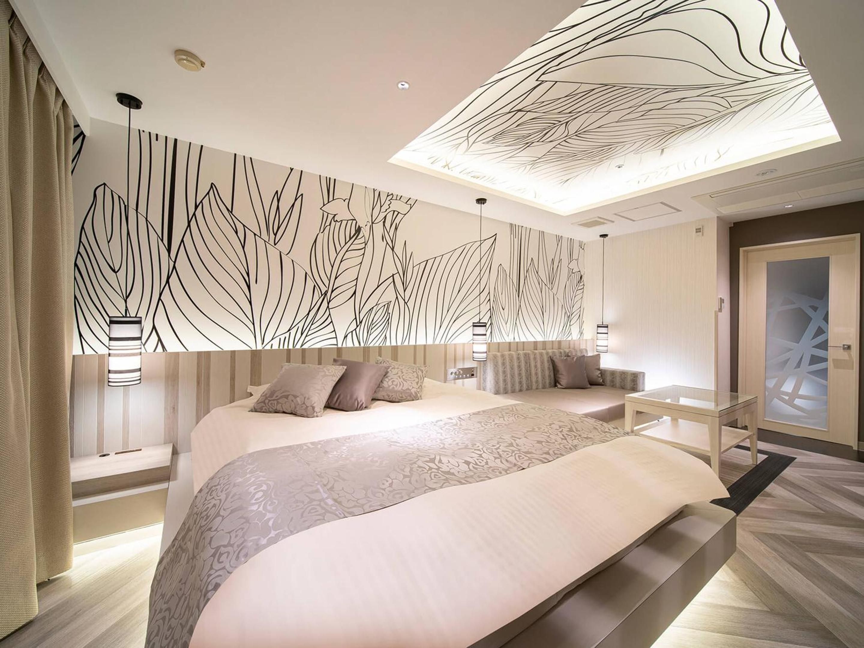 A modern bedroom with a large bed, a decorative wall, and a skylight.