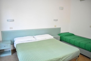 Une chambre avec un lit simple, une table de chevet et un couvre-lit vert.