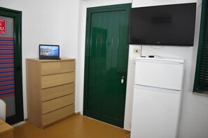 A room with a green door, a white refrigerator, and a laptop on a wooden cabinet. - San Nicola Centro Turistico (Peschici)