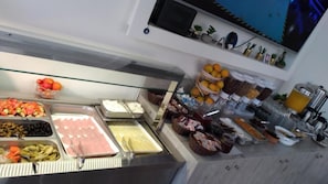 Un bufé con diversas opciones de comida, incluyendo frutas, verduras y carnes.