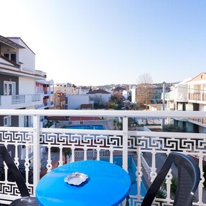 A balcony with a blue table and chairs, white railing, and a view of the cityscape. - Ralitsa Hotel (Thasos)