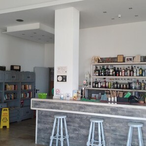 Zona de bar con mostrador, taburetes y estanterías llenas de botellas.