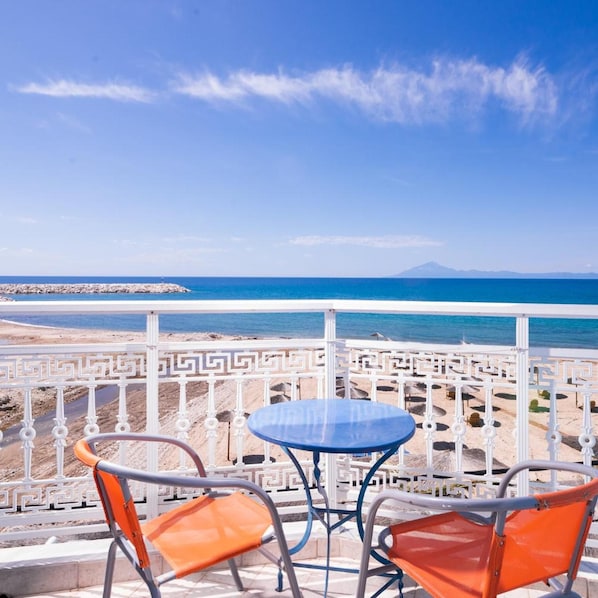Una terraza con una mesa y dos sillas con vista a una playa y al mar.