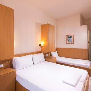 A hotel room with two beds, wooden headboards, a wall-mounted lamp, and a framed picture. - Ralitsa Hotel (Thasos)