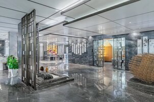 Un vestíbulo moderno con piso reflectante, un mostrador de recepción y una zona de estar con una fuente.