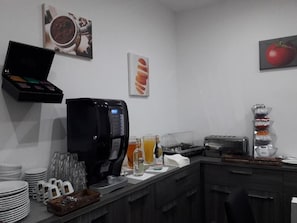 Una kitchenette equipada con cafetera, tostadora y una presentación de frutas.
