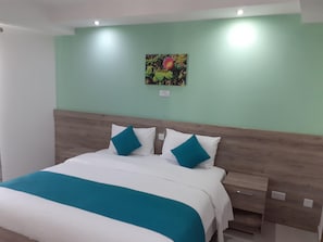 Habitación de hotel con una cama, una mesita de noche y una obra de arte colgada en la pared.
