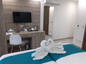 Una habitación de hotel con una cama, un escritorio, un televisor y un cesto de basura.